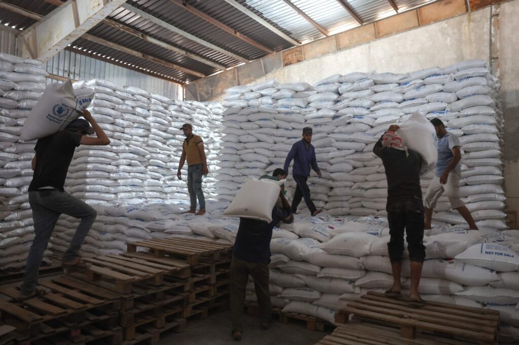 Workers unload bags of aid at a warehouse near the Syrian Bab al-Hawa border crossing with Türkiye, on July 10, 2023. (AFP Photo)