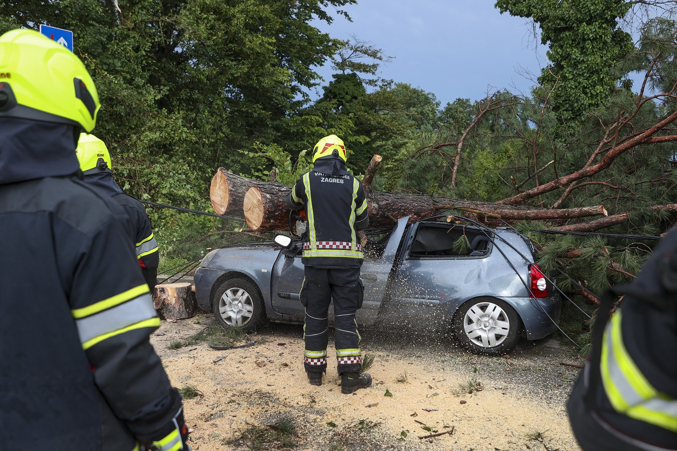 283787 Firefighters remove fallen tree branches from damaged parked car after a powerful storm, in Zagreb, Croatia, July 19, 2023. (AP Photo)