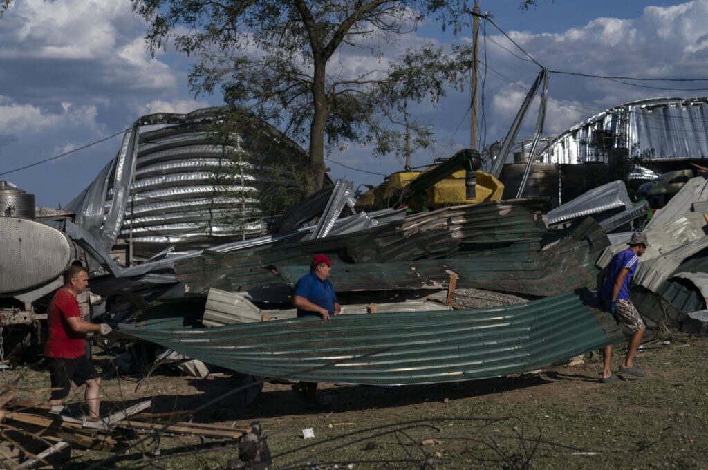 Workers carry a large piece of sheet metal from a destroyed warehouse at a grain facility following Russian missile attacks in Pavlivka, Ukraine, July 22, 2023. (AP Photo)