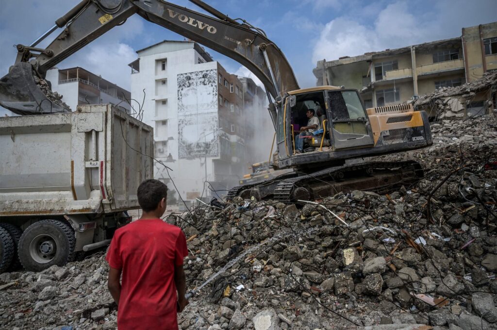 A construction worker sprays water as diggers remove the rubble of collapsed buildings after deadly earthquakes, Samandağ, Hatay, southeastern Türkiye, July 9, 2023. (AFP Photo)