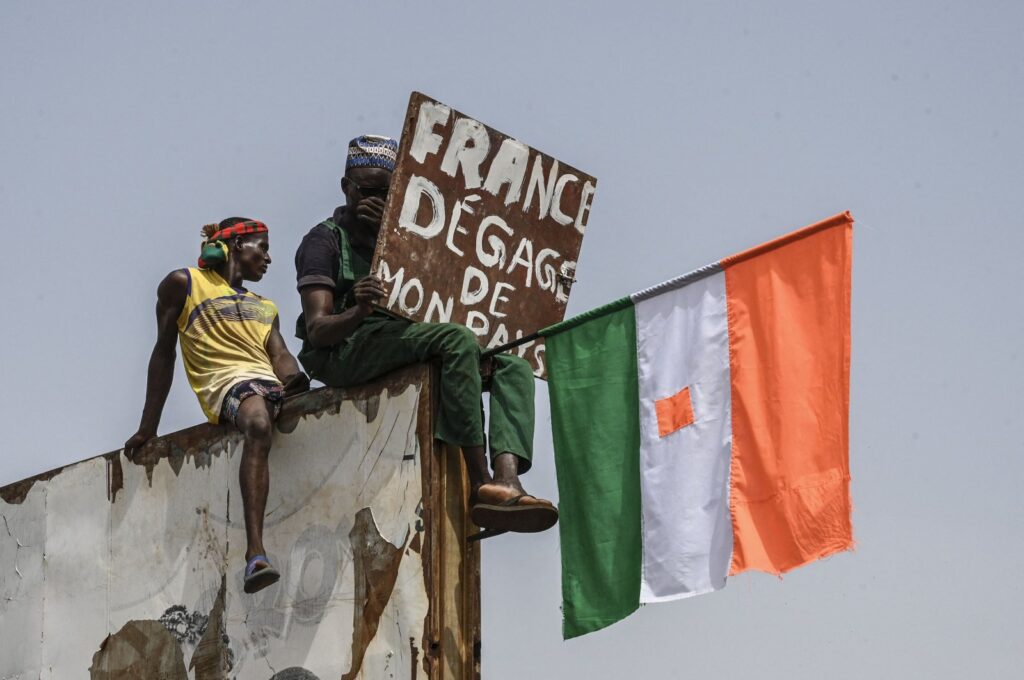 A man holds a placard and a Niger national flag as they protest outside the Niger and French airbase, Niamey, Niger, Sept. 2, 2023. (AFP Photo)