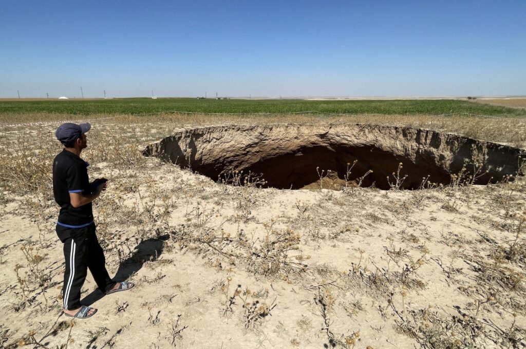 A man is seen standing close to a large sinkhole formed in the Karapınar district of central Konya province, Türkiye, Sept. 6, 2023. (AA Photo)