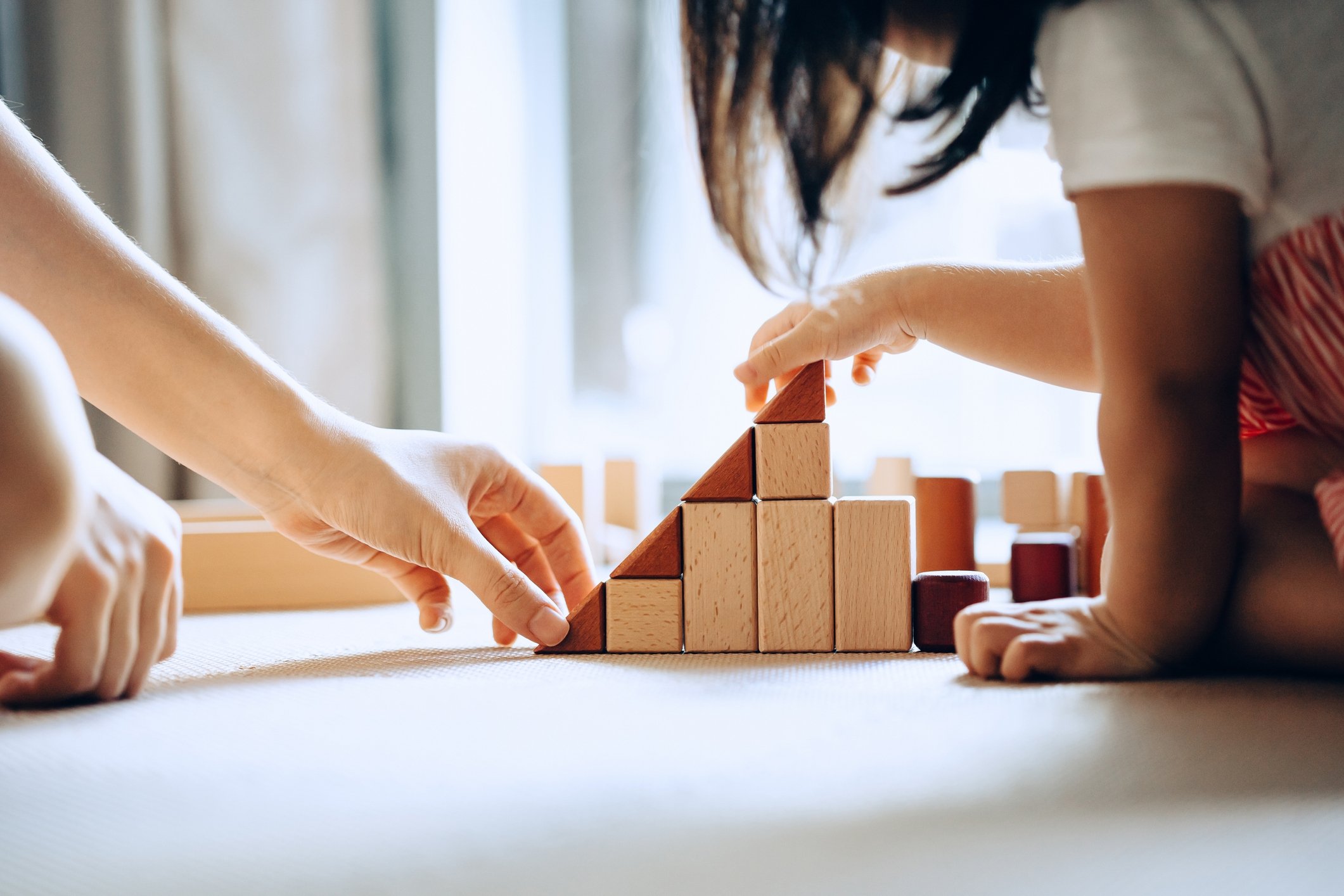 303034 A mother and her little daughter playing with wooden building blocks together, July 16, 2020. (Getty Images Photo)