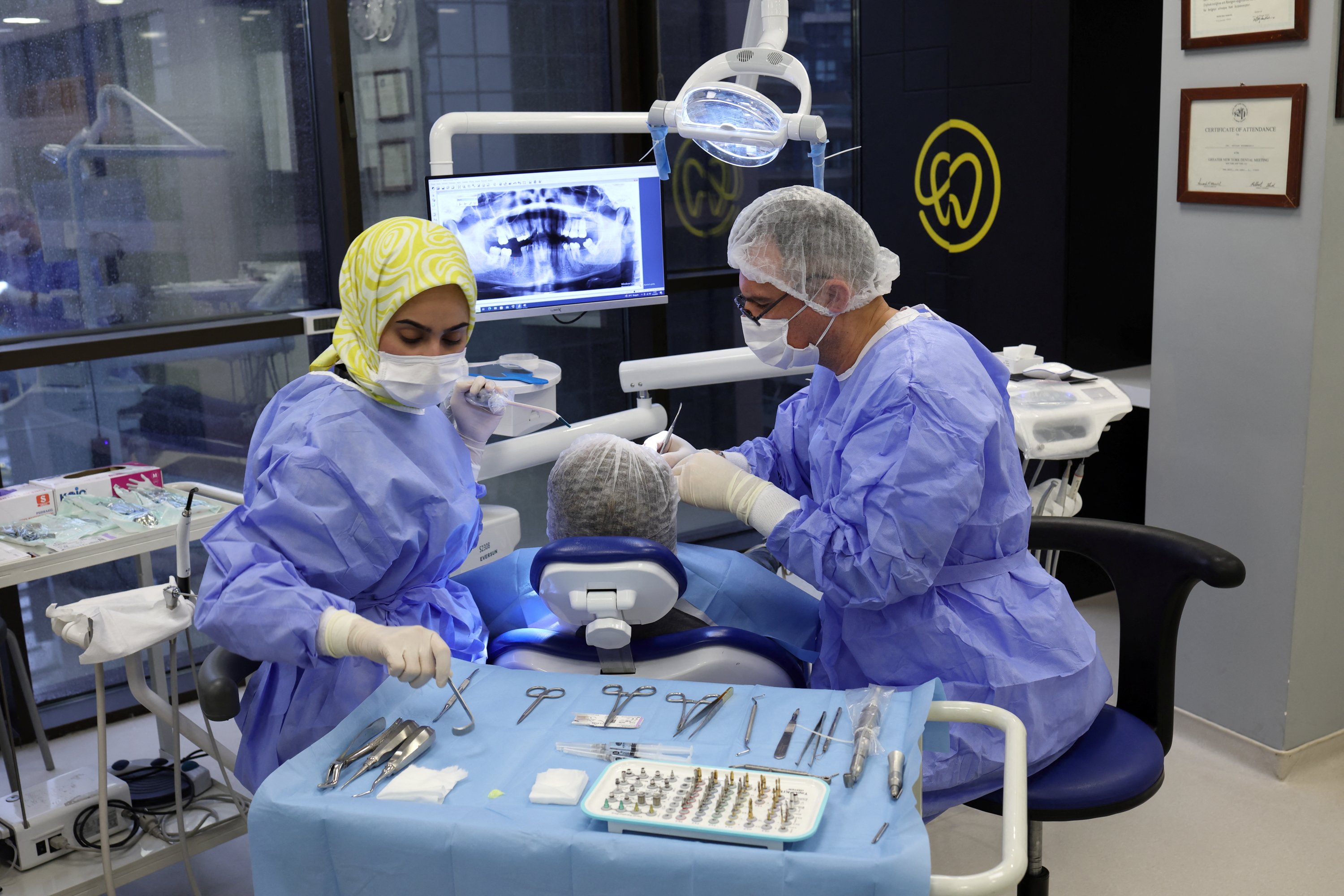304913 Turkish dentist Ertan Etemoğlu treats his patient Marion Parks, a 55-year-old British woman from a village near Ipswich, Suffolk, during a dental implant operation in Istanbul, Türkiye, Dec. 4, 2023. (Reuters Photo)