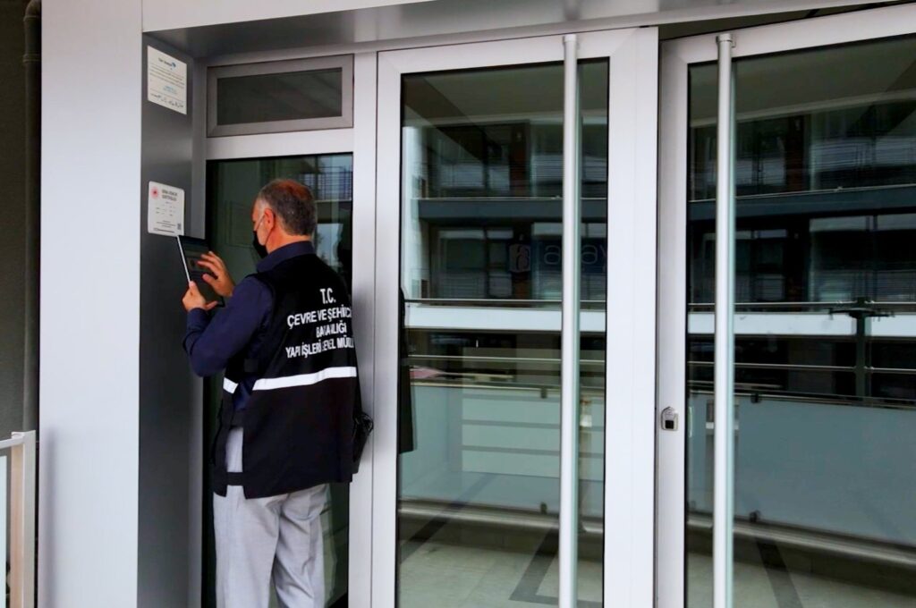 An officer from the Ministry of Environment, Urbanization and Climate Change scans the QR code of a building at an undisclosed location, Türkiye, Dec. 16, 2023. (DHA Photo)