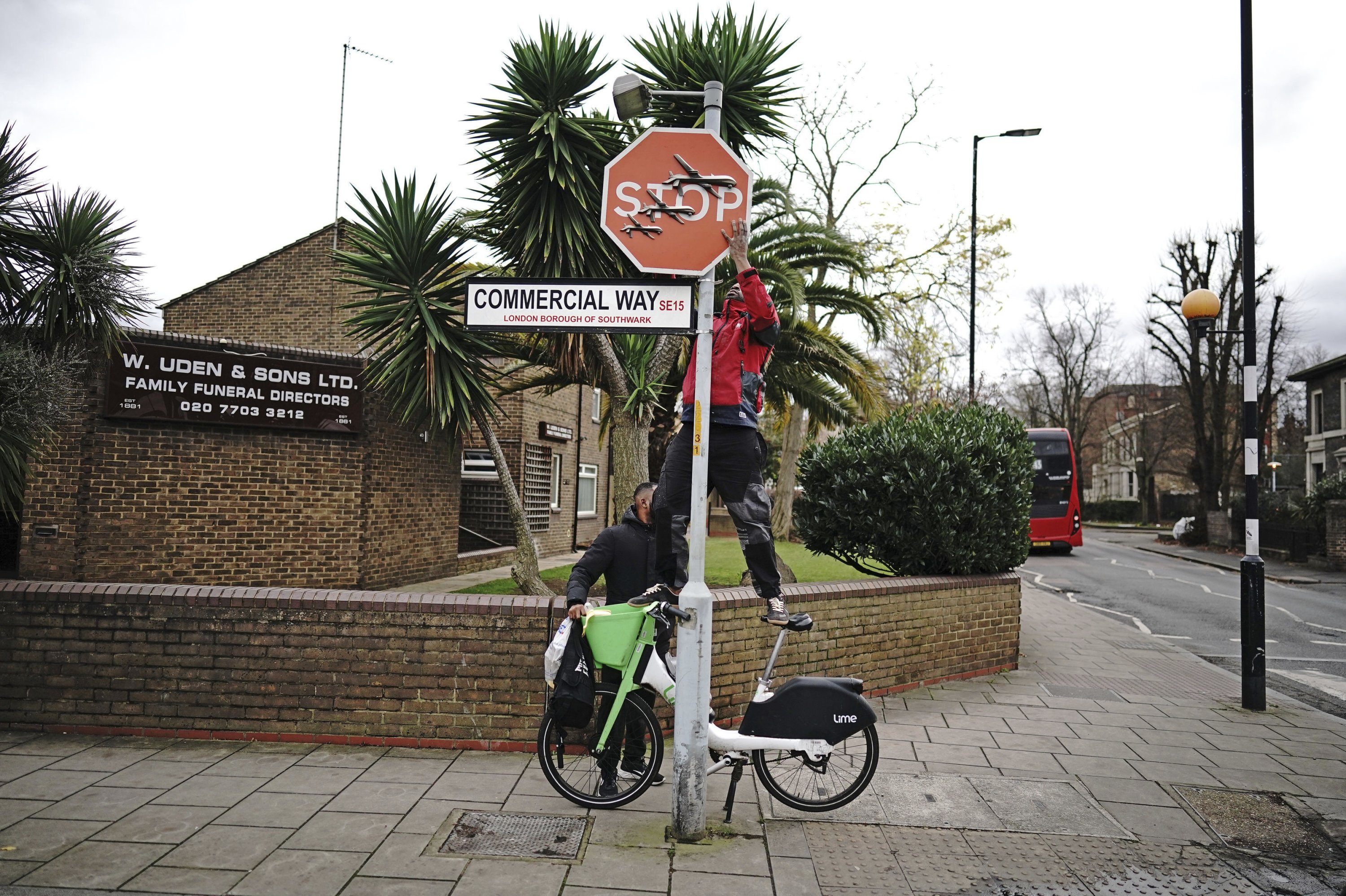 306825 A person removes a piece of artwork by Banksy, which shows what looks like three drones on a traffic stop sign, London, U.K., Dec. 22, 2023. (AP Photo)