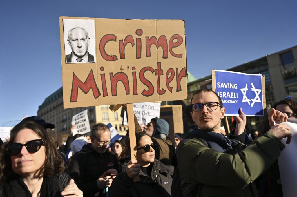 People protest with a sign reading "crime minister" at a demonstration at the Brandenburg Gate in Berlin against the judicial reform of Israel's Prime Minister Benjamin Netanyahu who was on a visit in Berlin, Germany, March 16, 2023. (AP File Photo)