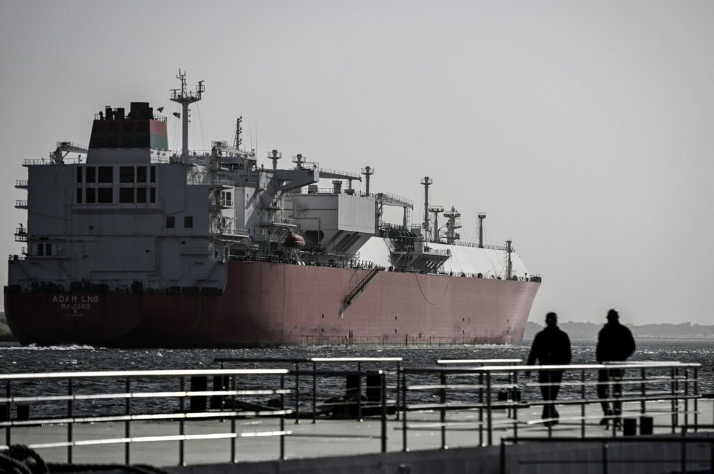 Two men watch a ship crossing the Suez Canal toward the Red Sea in Ismailia, Egypt, Dec. 22, 2023. (EPA Photo)