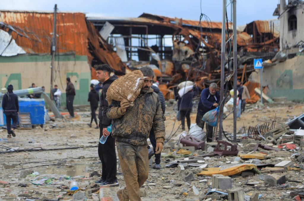 A Palestinian man carries a bag of flour from an aid truck near an Israeli checkpoint, as Gaza residents face crisis levels of hunger, amid the ongoing conflict between Israel and Hamas, in Gaza City Jan. 27, 2024. (Reuters Photo)