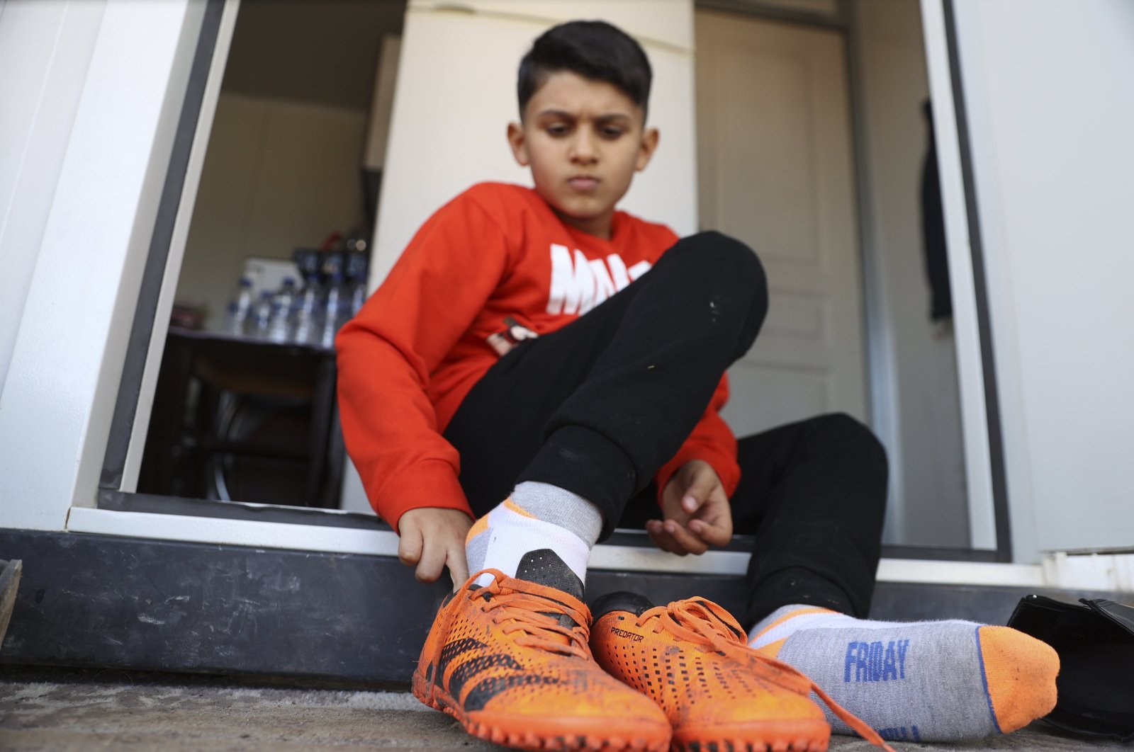 Southeastern Türkiye earthquake survivor Semih Ege Inci puts on his football cleats for training, Gaziantep, Türkiye, Feb. 5, 2024. (AA Photo)