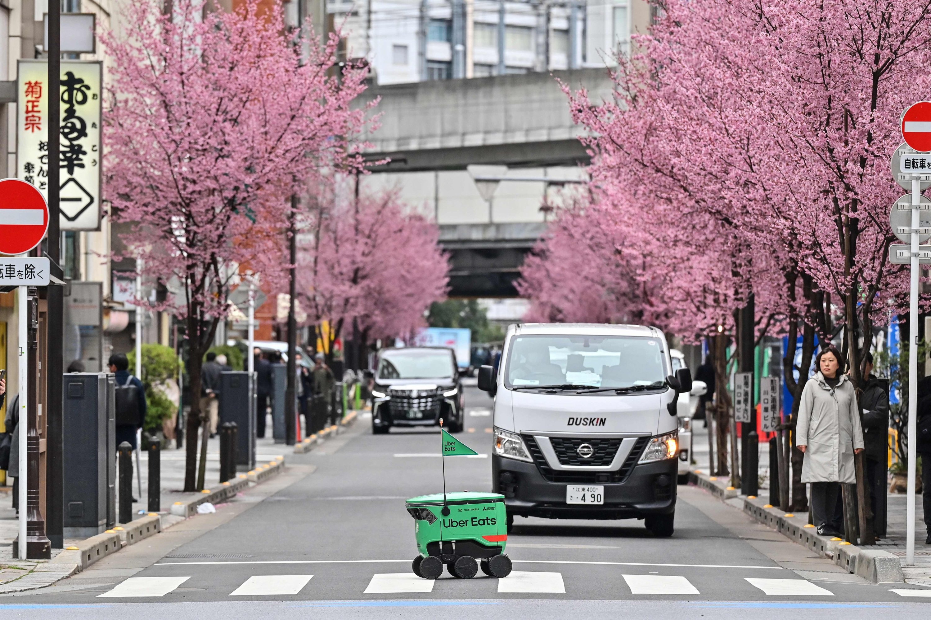 318085 An unmanned robot (C) navigates across a street during a demonstration of a robot delivery service by Uber Eats Japan, Mitsubishi Electric and robot developer Cartken in downtown Tokyo, Japan, March 5, 2024. (AFP Photo)
