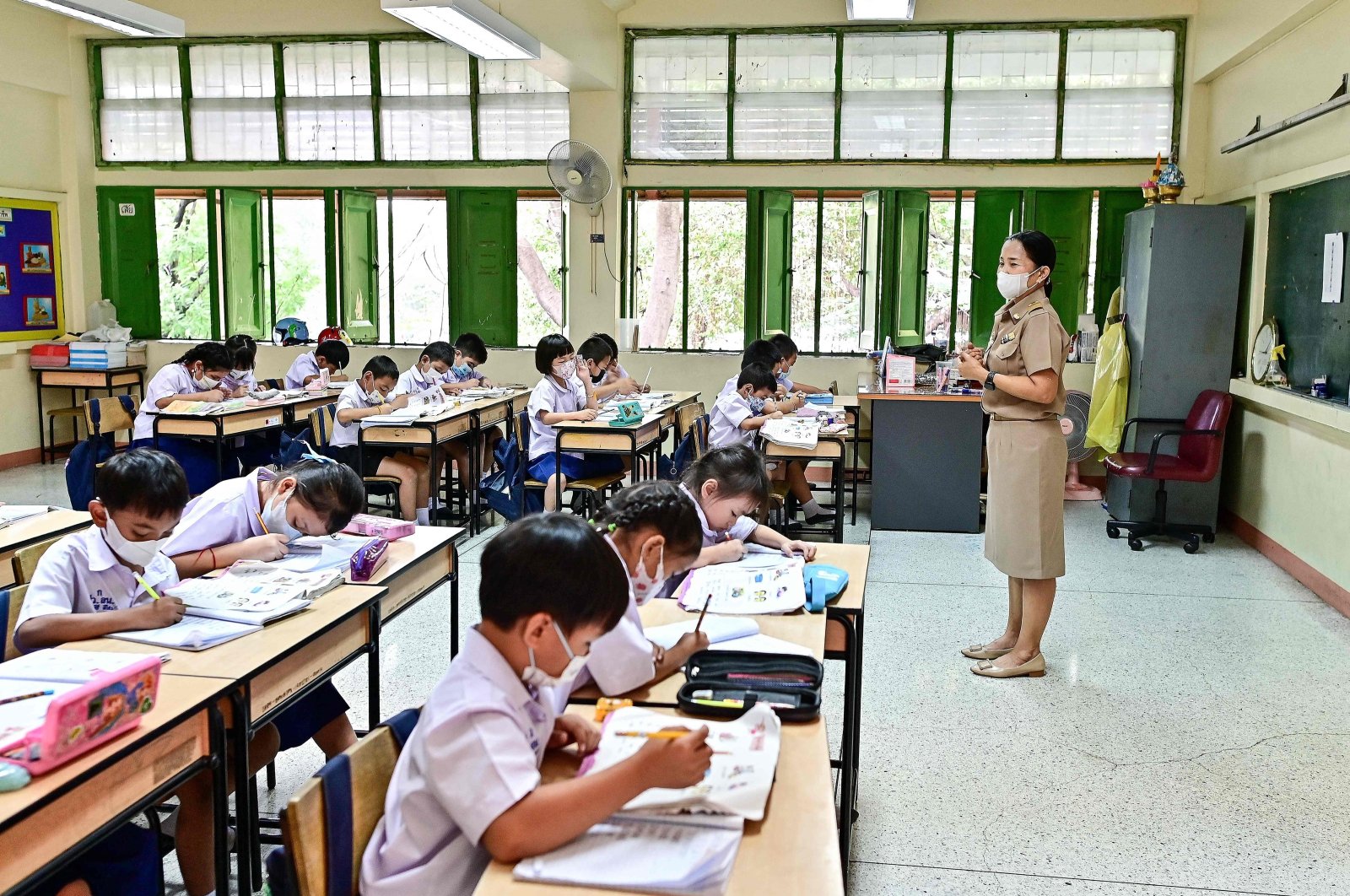 Students at Suanlumpinee School in Bangkok wear face masks while singing the national anthem amid traffic pollution outside their open classroom windows, Bangkok, Thailand, Jan. 22, 2024. (AFP Photo)