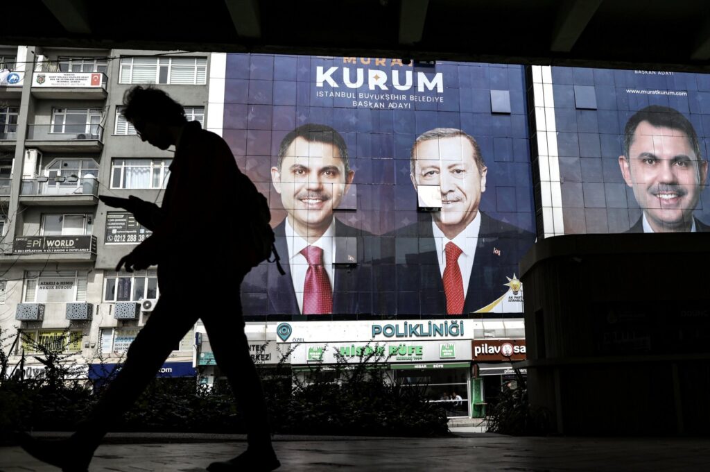 A person walks past images of President Recep Tayyip Erdoğan (C) and Justice and Development Party's (AK) Istanbul mayoral candidate Murat Kurum (L, R) as part of the campaign for the upcoming local elections in Istanbul, Türkiye, March 27, 2024. (EPA Photo)