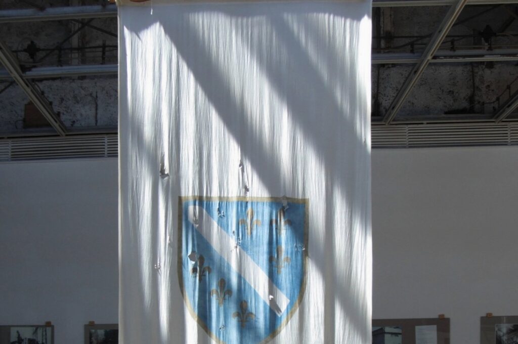 Now displayed in the History Museum, the old Bosnian flag bears the scars of shrapnel, serving as a poignant reminder of the nation's tumultuous past. (Wikipedia Photo)