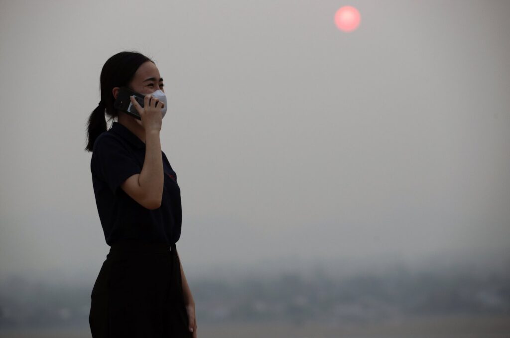 A Thai woman speaking on a mobile phone wears a mask amid smog from heavy concentrations of fine particulates matter PM2.5, in Chiang Mai province, northern Thailand, March 15, 2024. (EPA Photo)