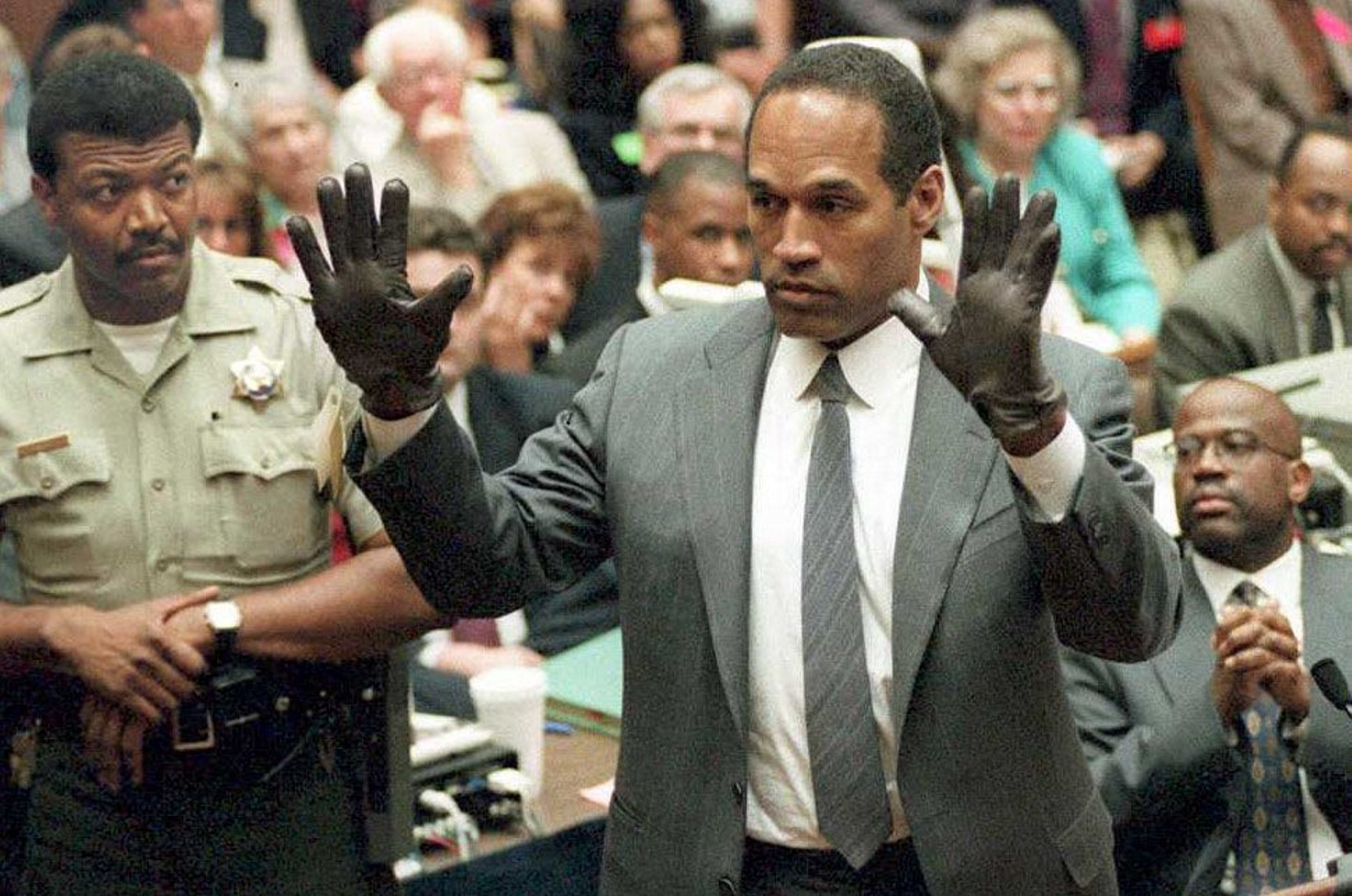323284 O.J. Simpson shows the jury a new pair of Aris extra-large gloves, similar to the gloves found at the Bundy and Rockingham crime scene during his double murder trial in Los Angeles, California, June 21, 1995. (AFP Photo)