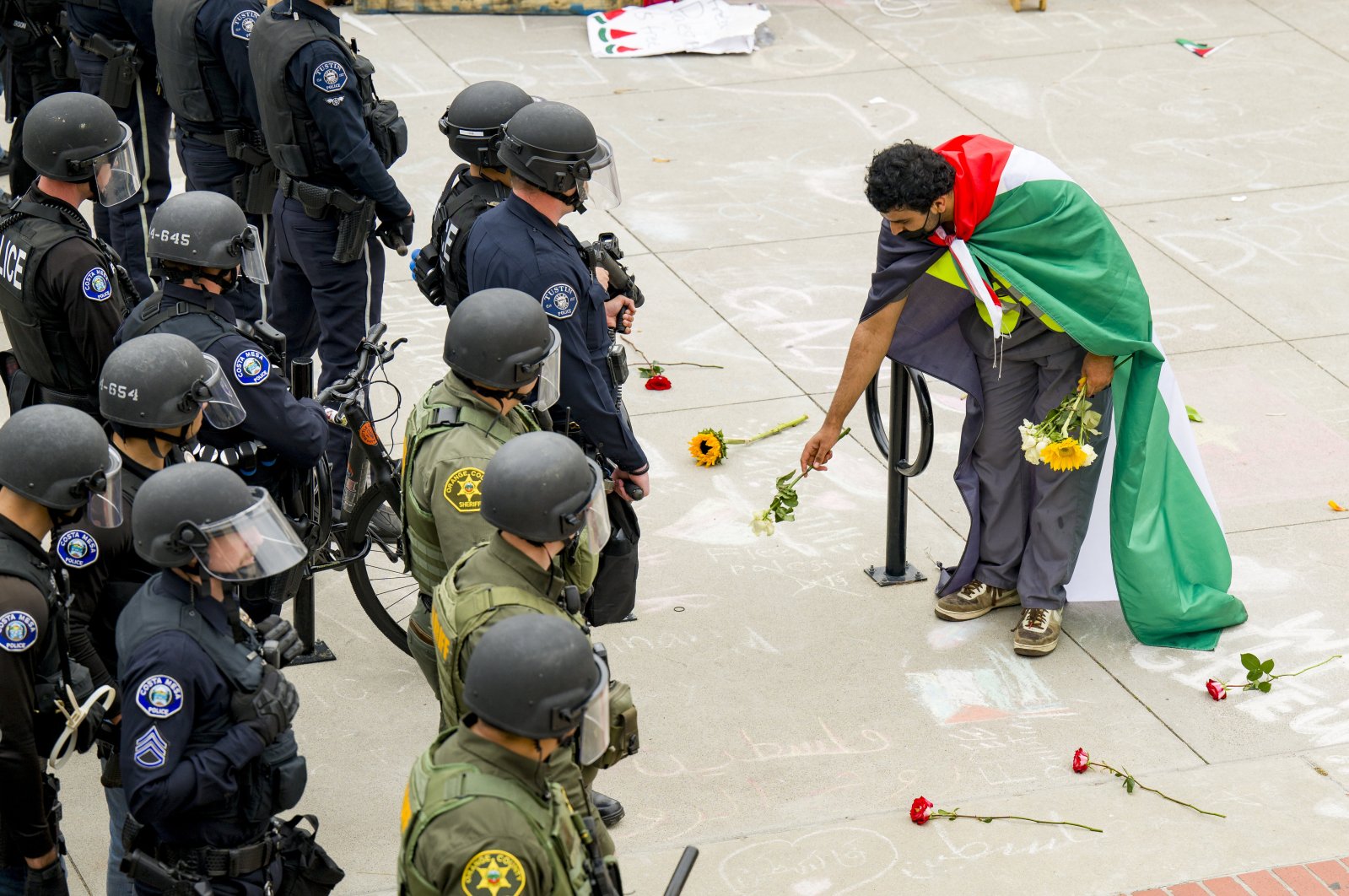 A supporter of a pro-Palestinian encampment places flowers at the feet of police at the University of California, Irvine, U.S., May 15, 2024. (AP Photo)