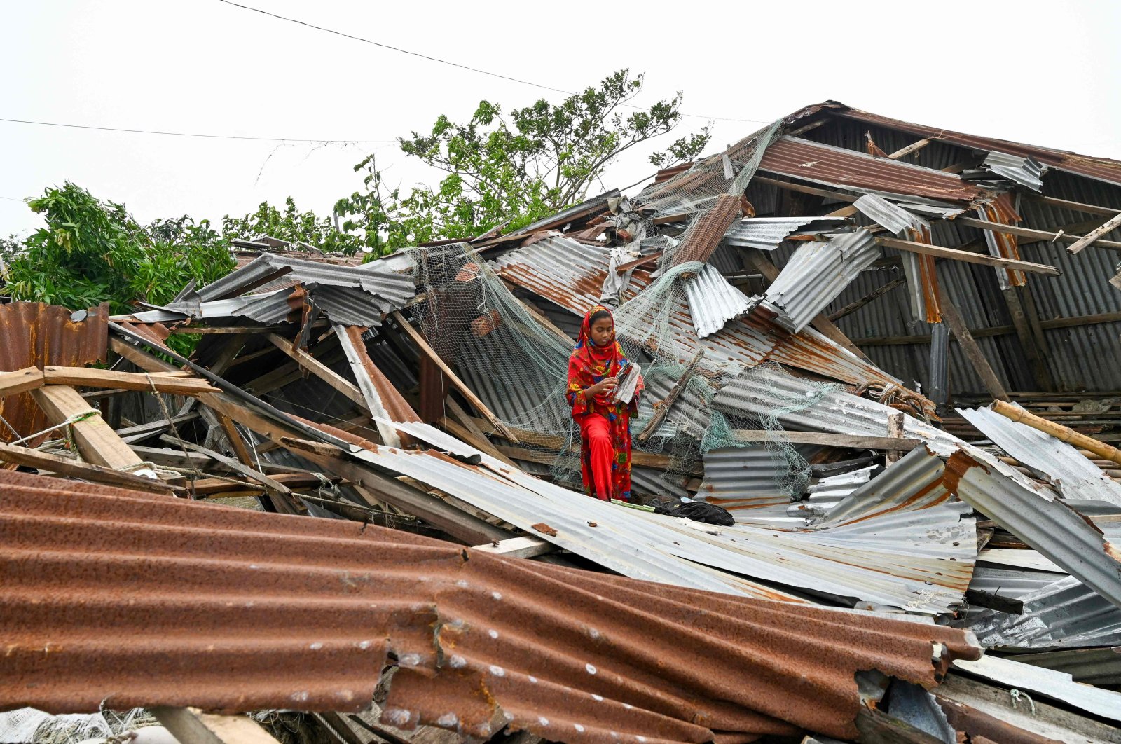 A girl walks amid her damaged house after cyclone Remal's landfall in Patuakhalim Bangladesh, May 28, 2024. (AFP Photo)