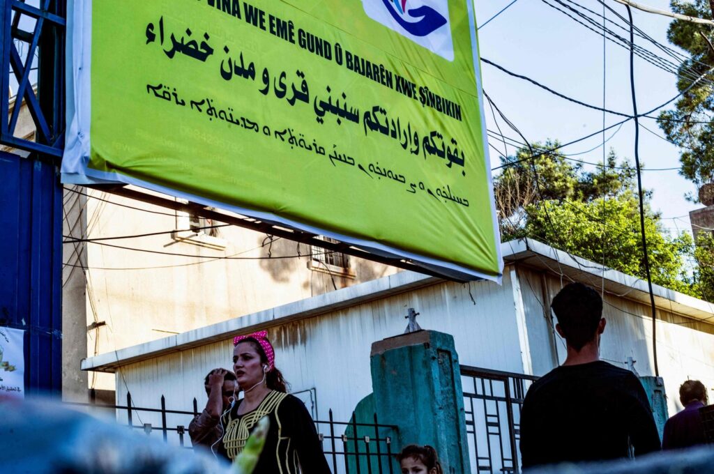 Syrian Kurdish women walk past a campaign banner for the PKK/YPG's so-called elections in the northeastern city of Qamishli, Syria, June 6, 2024. (AFP Photo)