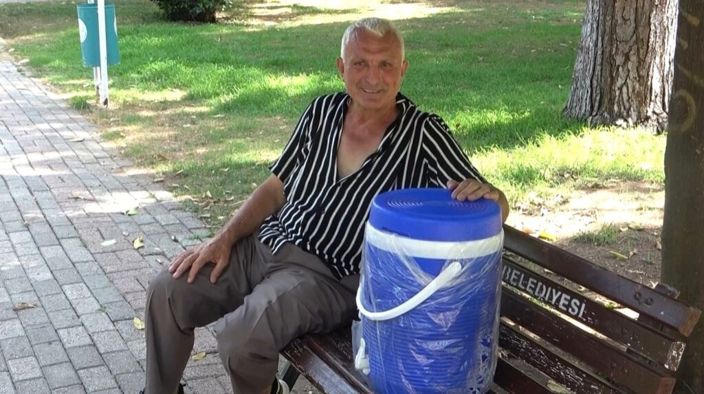 A man tries to cool off in the park with his thermos in Adana, Türkiye, June 18, 2024. (IHA Photo)
