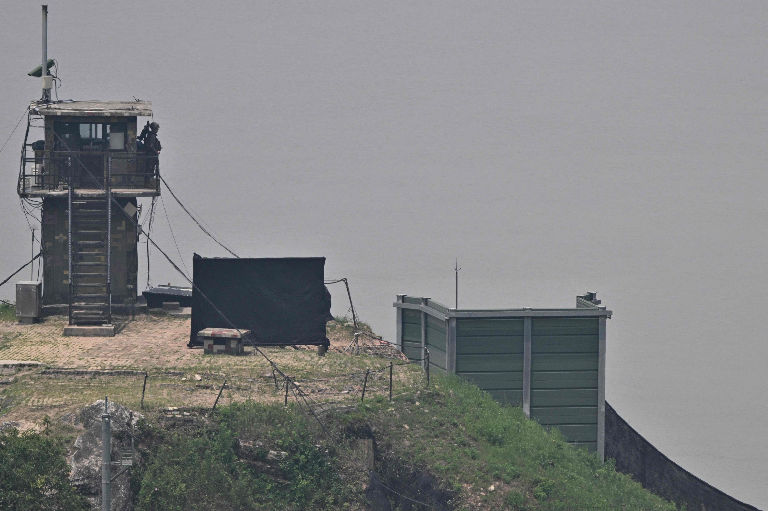 333359 A South Korean soldier stands guard near a military facility (R, green box) where loudspeakers dismantled in 2018 used to be, near the demilitarized zone separating the two Koreas, Paju, June 11, 2024. (AFP Photo)