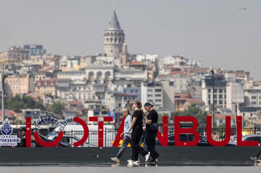 People walk past an Istanbul sign as Galata Tower is seen in the background in Istanbul, Türkiye, June 13, 2024. (AFP Photo)