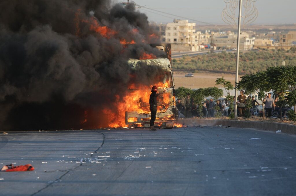 A protester stands in front a burning Turkish truck during protests against Türkiye in a Syrian opposition-held area north of Aleppo, Syria, July 1, 2024. (AFP Photo)