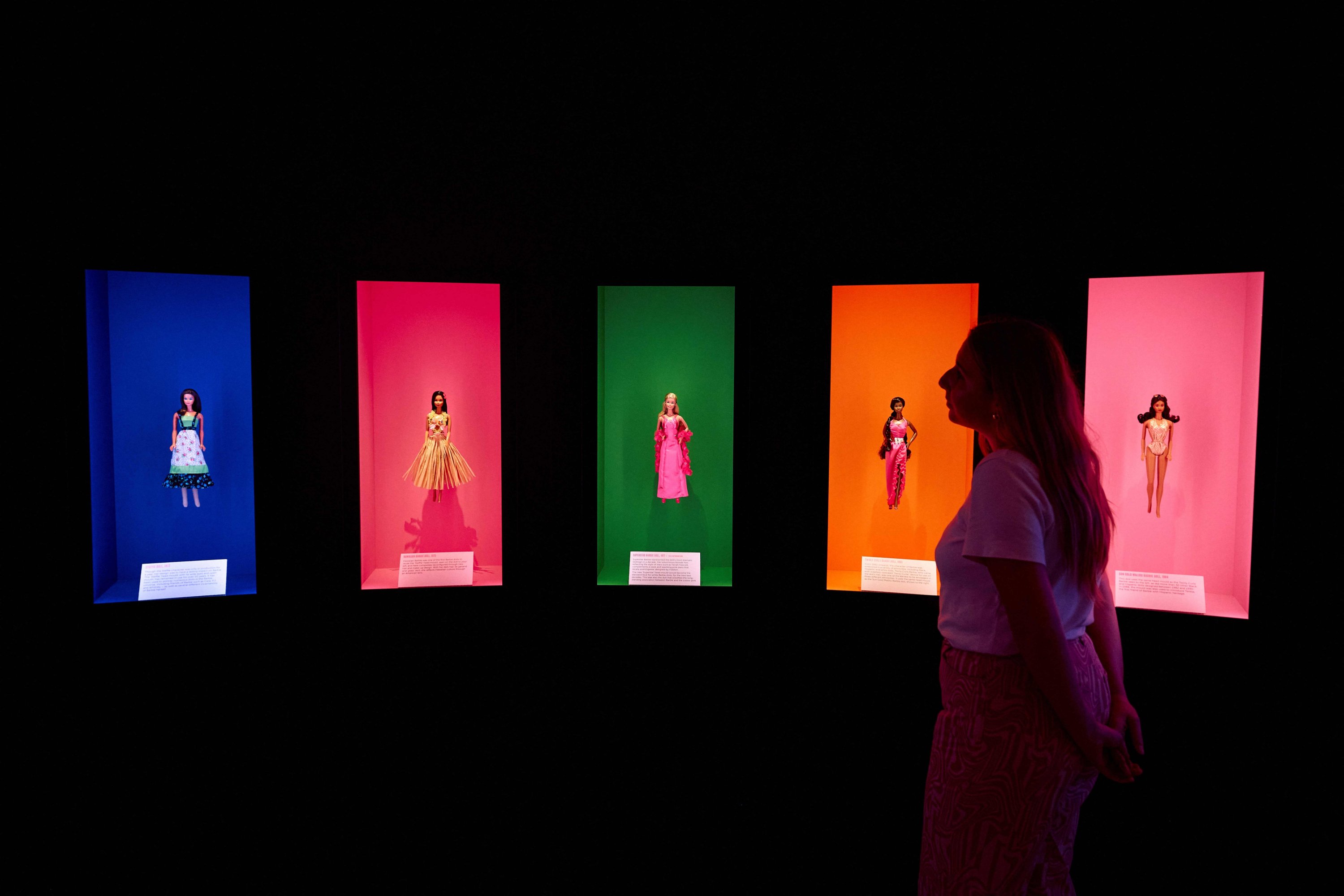 335542 A gallery assistant poses with various Barbie dolls displayed during the