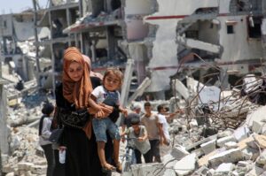 A Palestinian woman holds her daughter as she walks past the rubble of houses destroyed during the Israeli military offensive, Khan Younis, Gaza Strip, Palestine, July 10, 2024. (Reuters Photo)