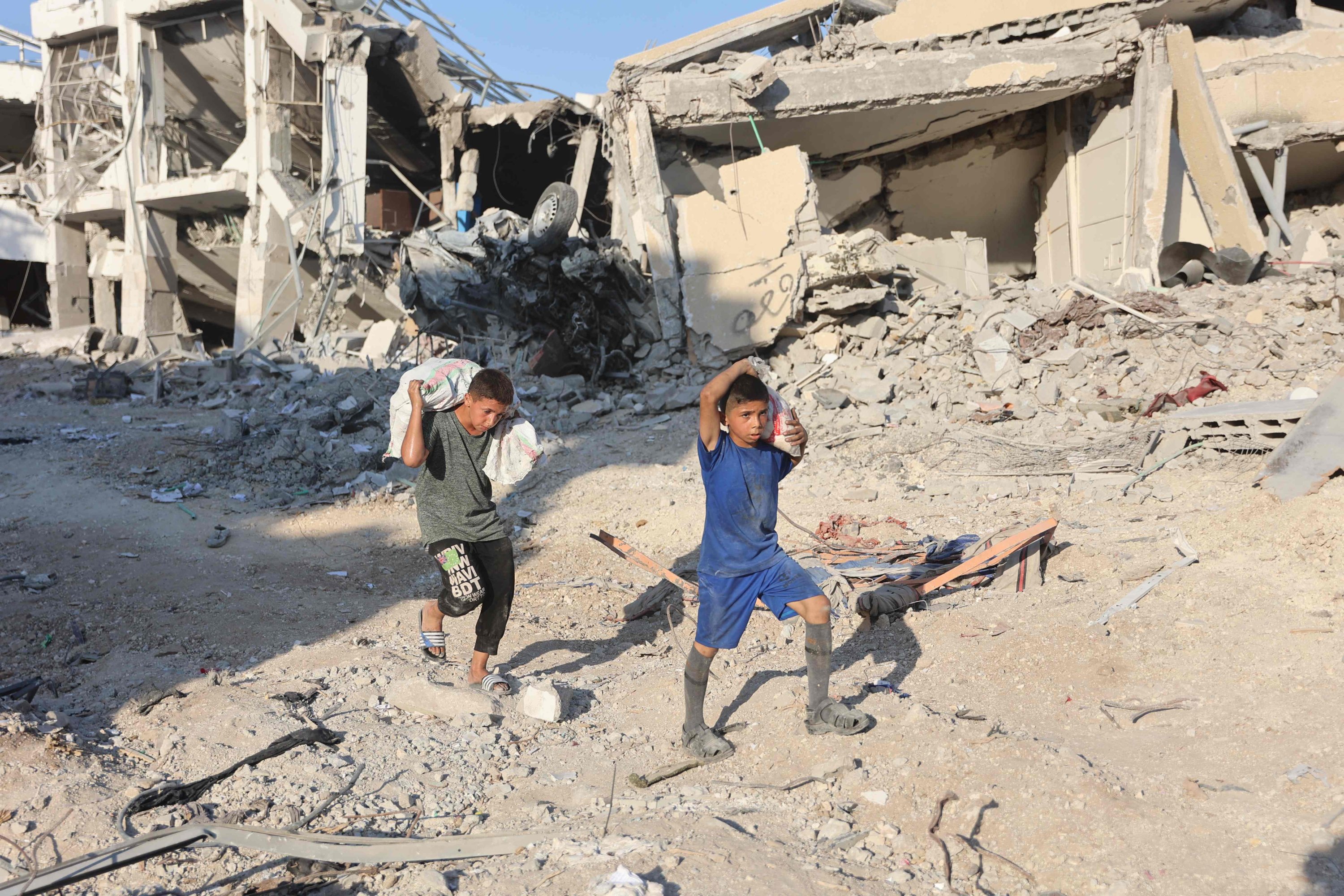 336312 Palestinian boys carry sacks as they walk on the rubble past destroyed buildings after the Israeli military withdrew from the Shujaiya neighborhood, east of Gaza City, Palestine, July 10, 2024. (AFP Photo)
