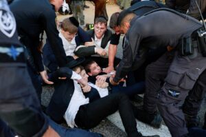 Young men lay on the ground, as Ultra-Orthodox Jewish men protest after an Israeli Supreme Court ruling that requires the state to begin drafting ultra-Orthodox Jewish seminary students to the military, in Bnei Brak, Israel July 16, 2024. (Reuters Photo)