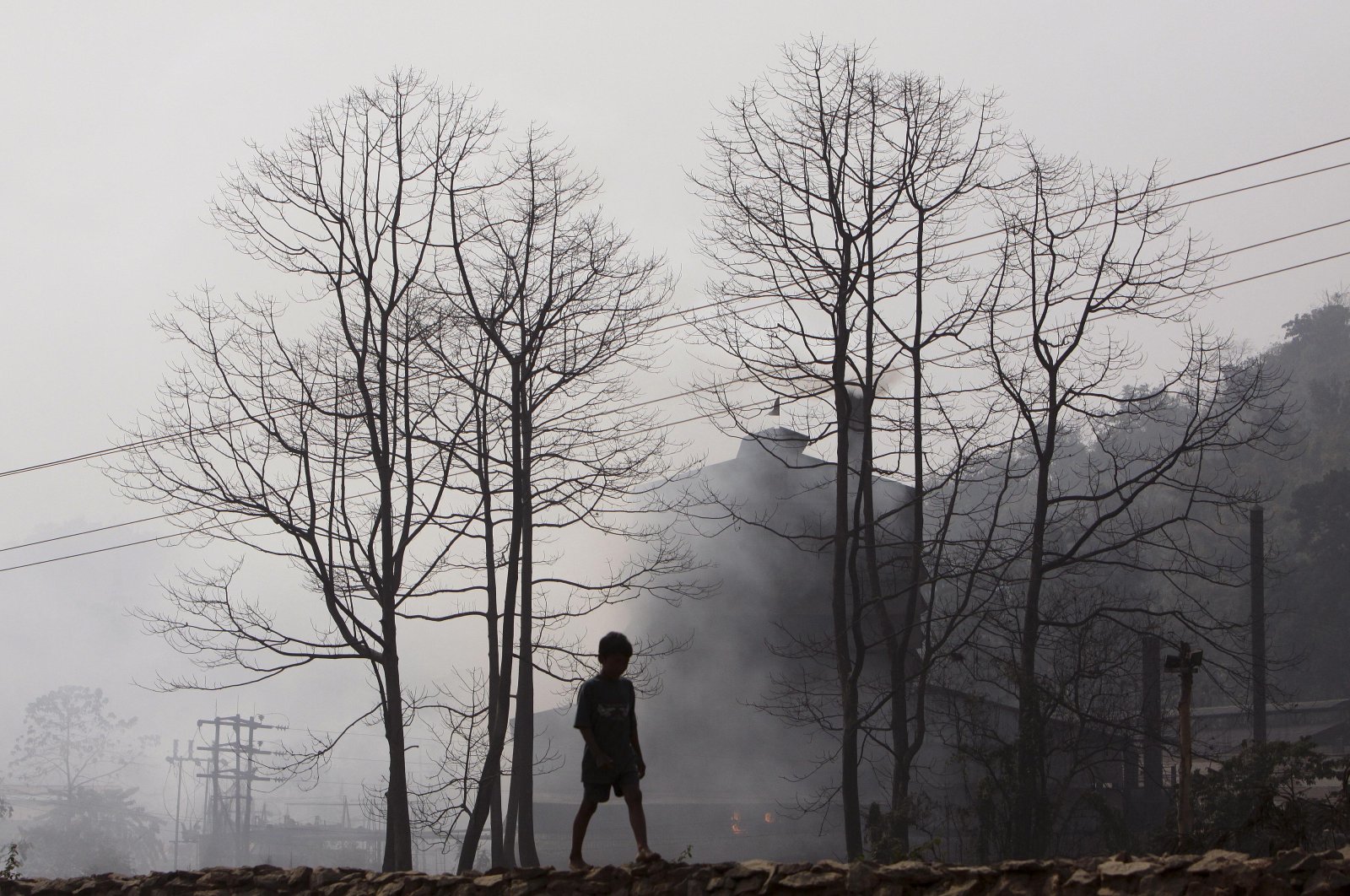 A boy walks past smoke rising from an industrial site on the outskirts of Gauhati, India, Feb. 5, 2010. (AP Photo)