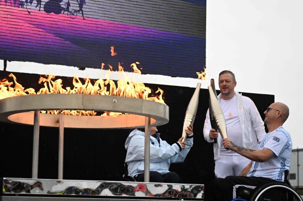 Britain's Helene Raynsford (L) and Britain's Gregor Ewan, light the torch of International Paralympic Committee President Andrew Parsons (C), lit from the cauldron, during the Paralympic torch-lighting ceremony at Stoke Mandeville, Aylesbury, U.K., Aug. 24, 2024. (AFP Photo)