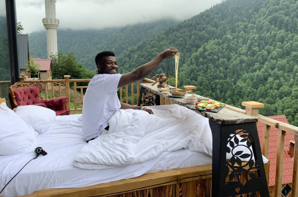 Ghanaian tourist Yahya Abulli enjoys breakfast on the balcony of a wooden bungalow, Rize, northern Türkiye, Aug. 27, 2024. (DHA Photo)