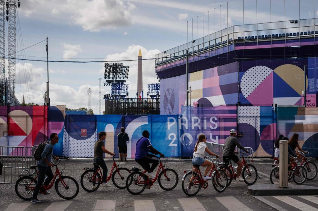 Cyclists ride past the Place de la Concorde Paralympic site covered in "Paris 2024" tarpaulins ahead of the Paris 2024 Paralympic Games, Paris, France, Aug. 21, 2024. (AFP Photo)