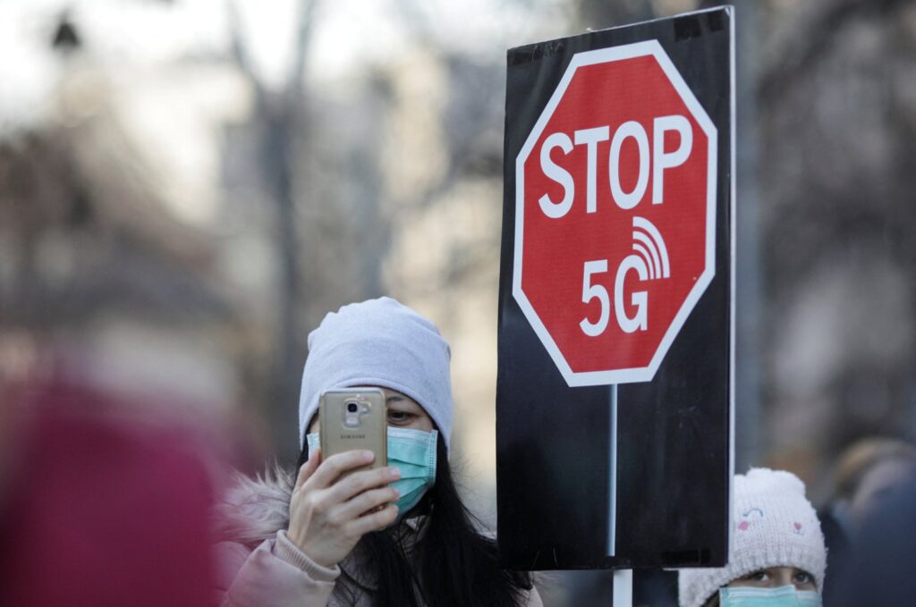 A woman uses her mobile phone while holding a placard reading " STOP 5G" during a protest against 5G technology, in Bucharest, Romania, Jan. 25, 2020. (Reuters File Photo)
