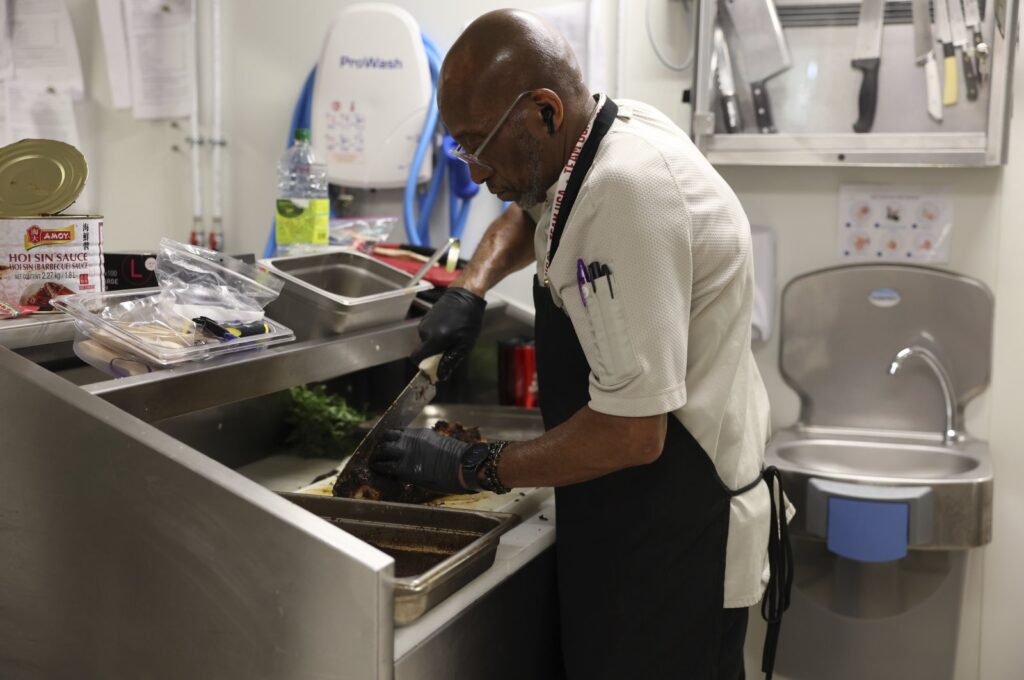 Kevin Oakes, cuts a rosemary pork loin with rosemary au jus in the kitchen of the United States Olympic and Paralympic Committee's High Performance Center during the Paralympic Games, Paris, France, Aug. 31, 2024. (AP Photo)