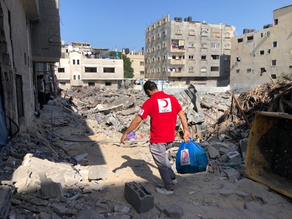 A Turkish Red Crescent team member delivers aid among the destroyed buildings in Gaza, Palestine, Oct. 6, 2024. (IHA Photo)