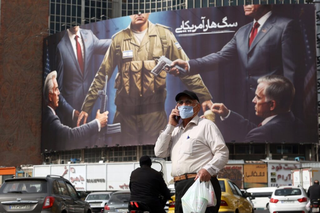 An elderly man walks past an anti-Israeli and U.S. billboard depicting an Israeli soldier receiving military supplies from the U.S. with the title "American rabid dog," at Tehran's Valiasr Square, Tehran, Iran, Oct. 28, 2024. (EPA Photo)
