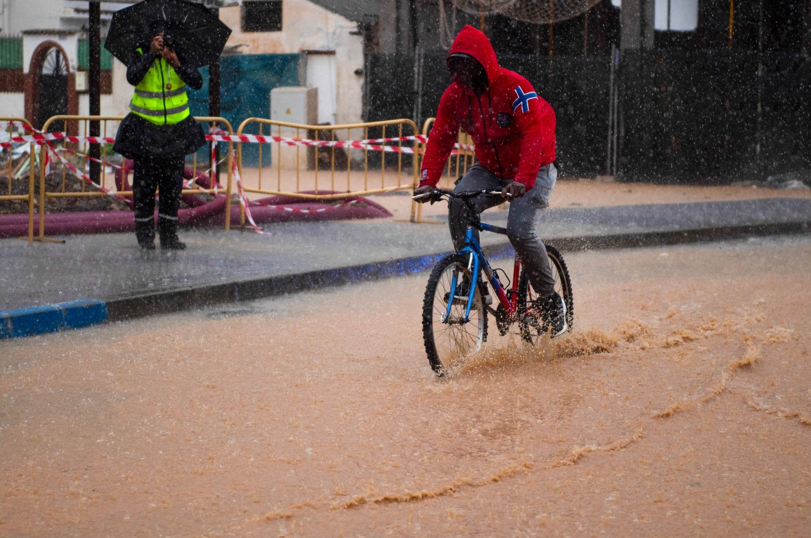 A man rides a bicycle down a flooded street, Campanillas, Malaga, Spain, Nov. 13, 2024. (AFP Photo)