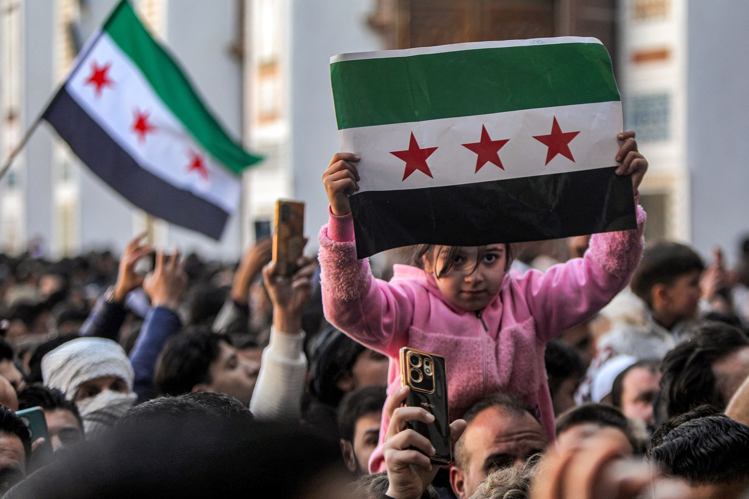 359422 A girl holds up an independence-era Syrian flag as she is lifted among people gathering in the courtyard of Umayyad Mosque in the old city of Damascus, Syria, Dec. 13, 2024. (AFP Photo)