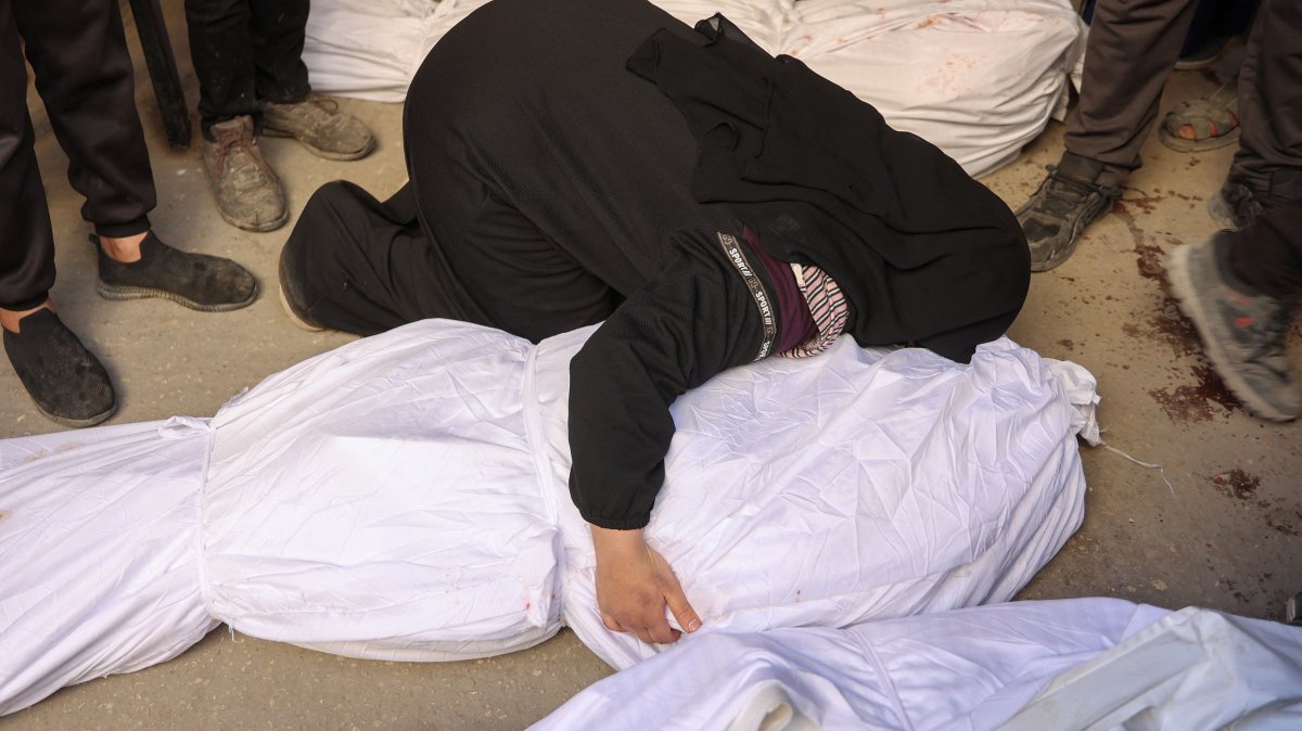 A woman mourns over a body wrapped in a white cloth outside the Baptist hospital, Gaza City, Palestine, Dec. 27, 2024. (AFP Photo)