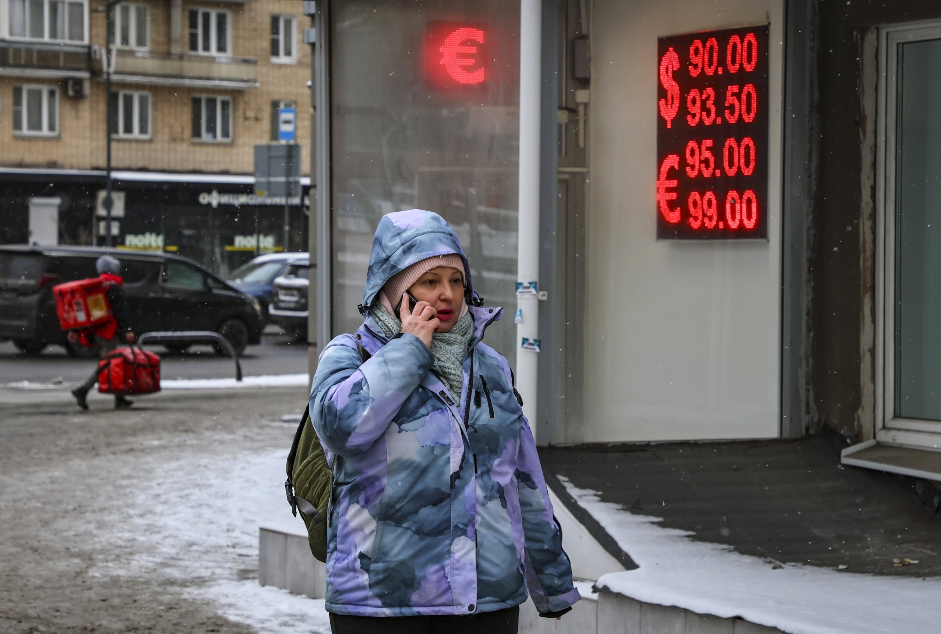 369932 A woman walks in front of an exchange office with an electronic panel displaying currency exchange rates against the Russian ruble, Moscow, Russia, Feb. 20, 2025. (EPA Photo)