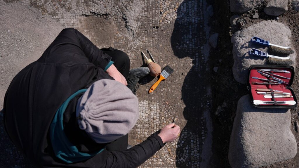 An archaeologist uncovers mosaic tiles in "Mosaic House" in the ancient city of Pergamon, Izmir, western Türkiye, Feb. 24, 2025. (AA Photo)