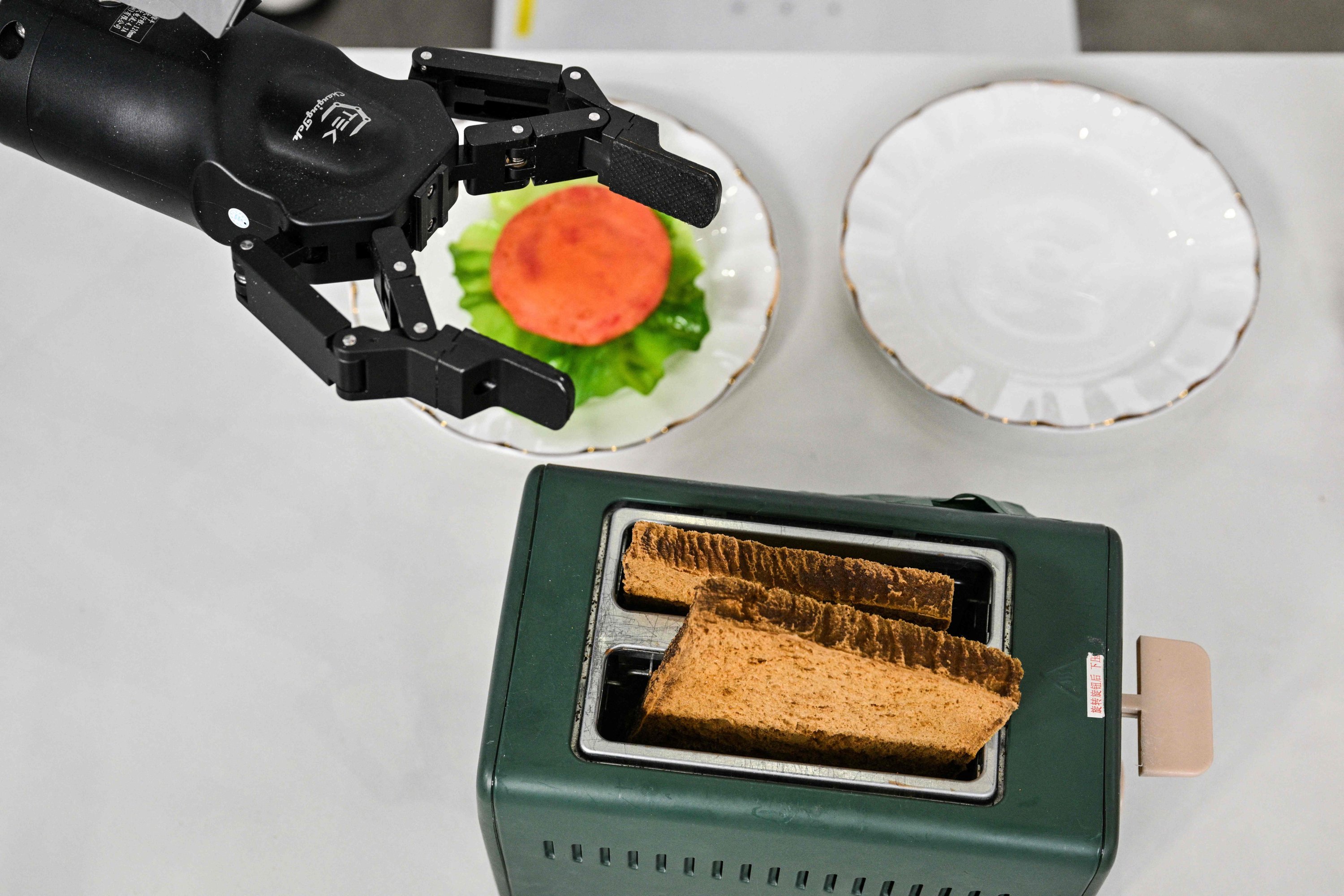 370726 A robot controlled by a remote puts bread in a toaster during the Global Developer Conference, organized by the Shanghai AI Industry Association, Shanghai, China, Feb. 21, 2025. (AFP Photo)