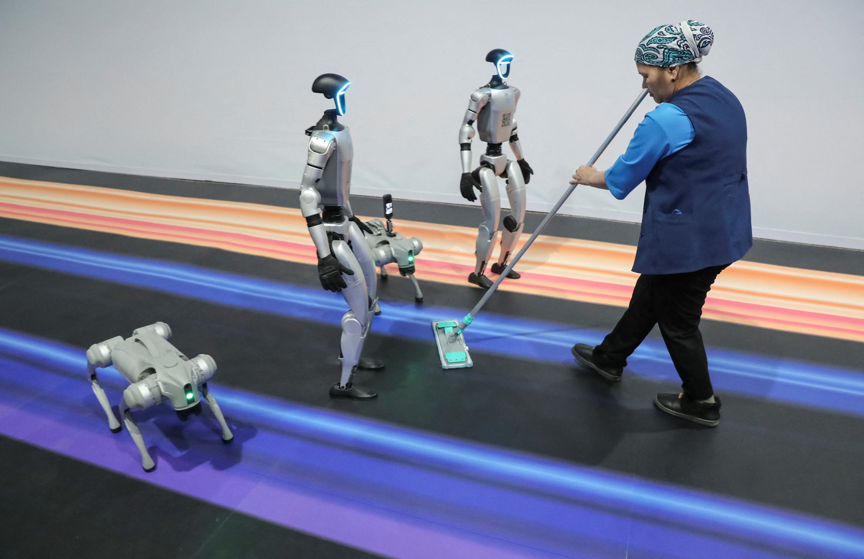 370728 A staff member cleans the floor next to robots during the Digital Almaty 2025 forum, Almaty, Kazakhstan, Jan. 31, 2025. (Reuters Photo)