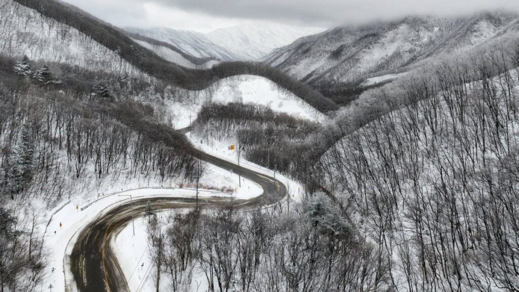 A curvy road passes through snow-covered hills and mountains in Gangneung, South Korea, March 3, 2025. (EPA Photo)