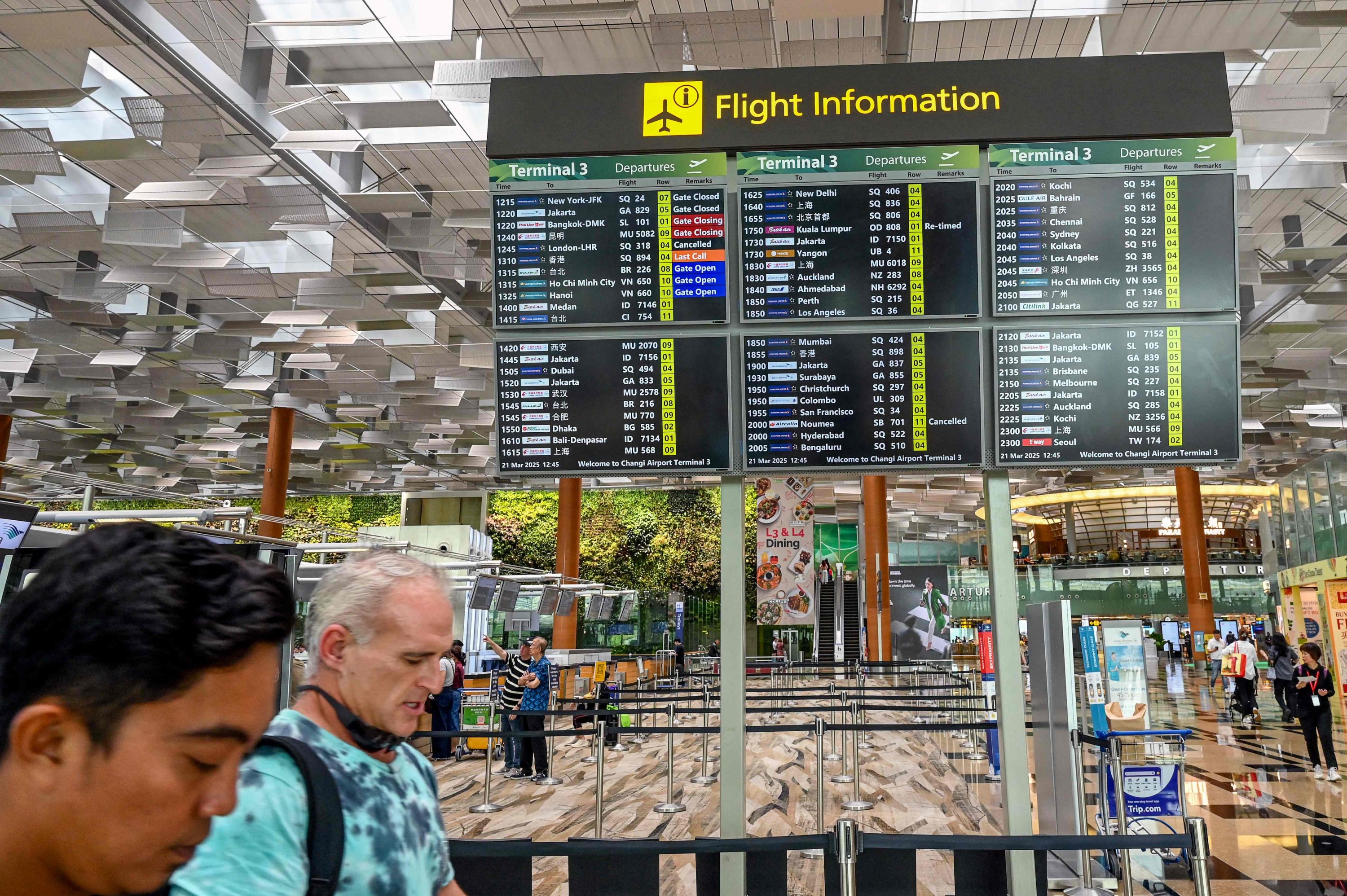 373990 People walk past a departure board displaying Singapore Airlines SQ318 flight to London Heathrow as canceled at Singapore Changi Airport, Singapore, March 21, 2025. (AFP Photo)