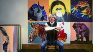 American pop artist Andy Warhol sits in front of several paintings in his "Endangered Species" series at his studio, the Factory, in Union Square, New York, U.S., April 12, 1983. (Getty Images Photo)