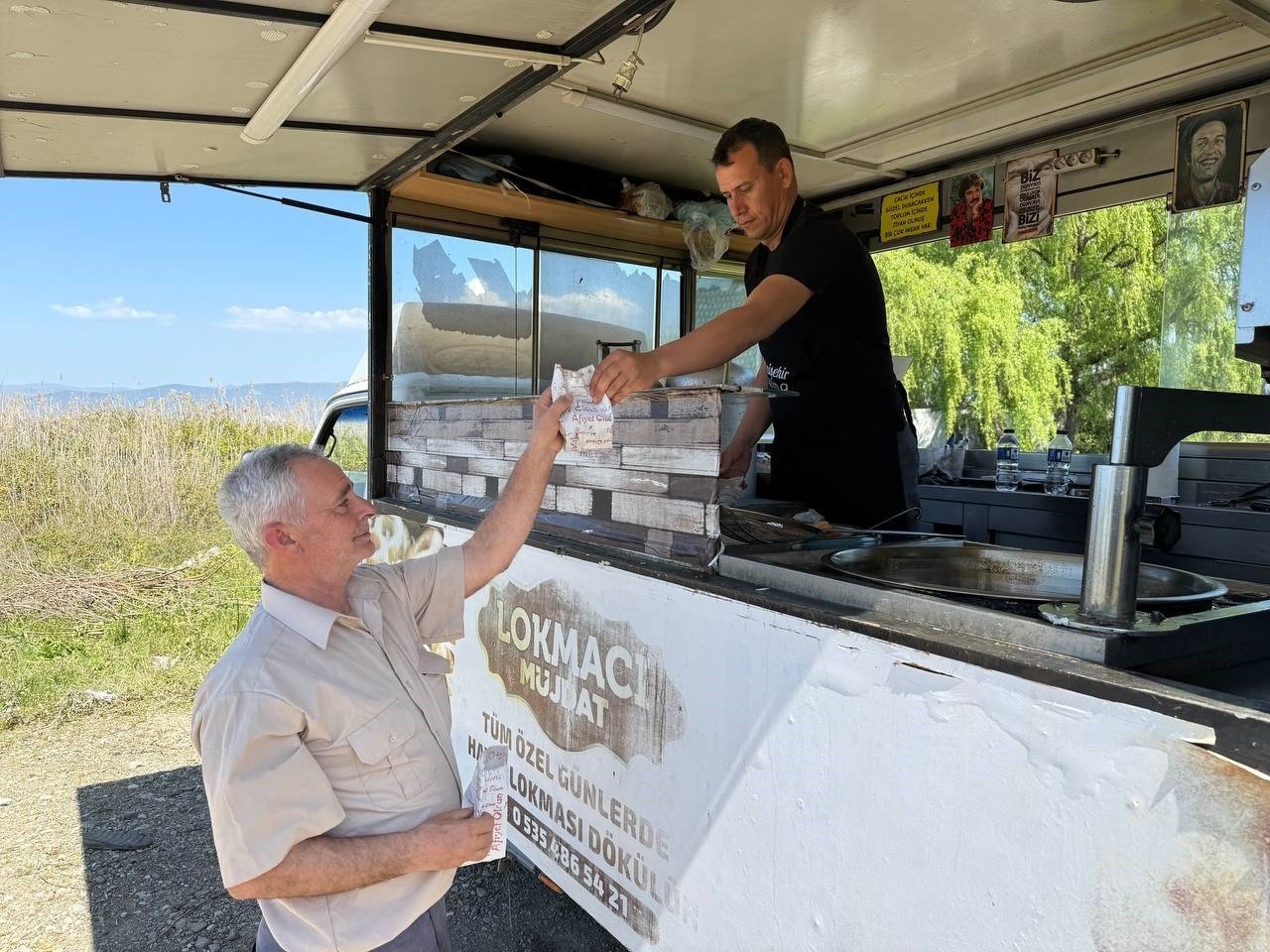A local shopkeeper distributes traditional lokma to a resident in memory of Pope Francis following his death, in Iznik, Bursa, northwestern Türkiye, April 21, 2025. (IHA Photo)